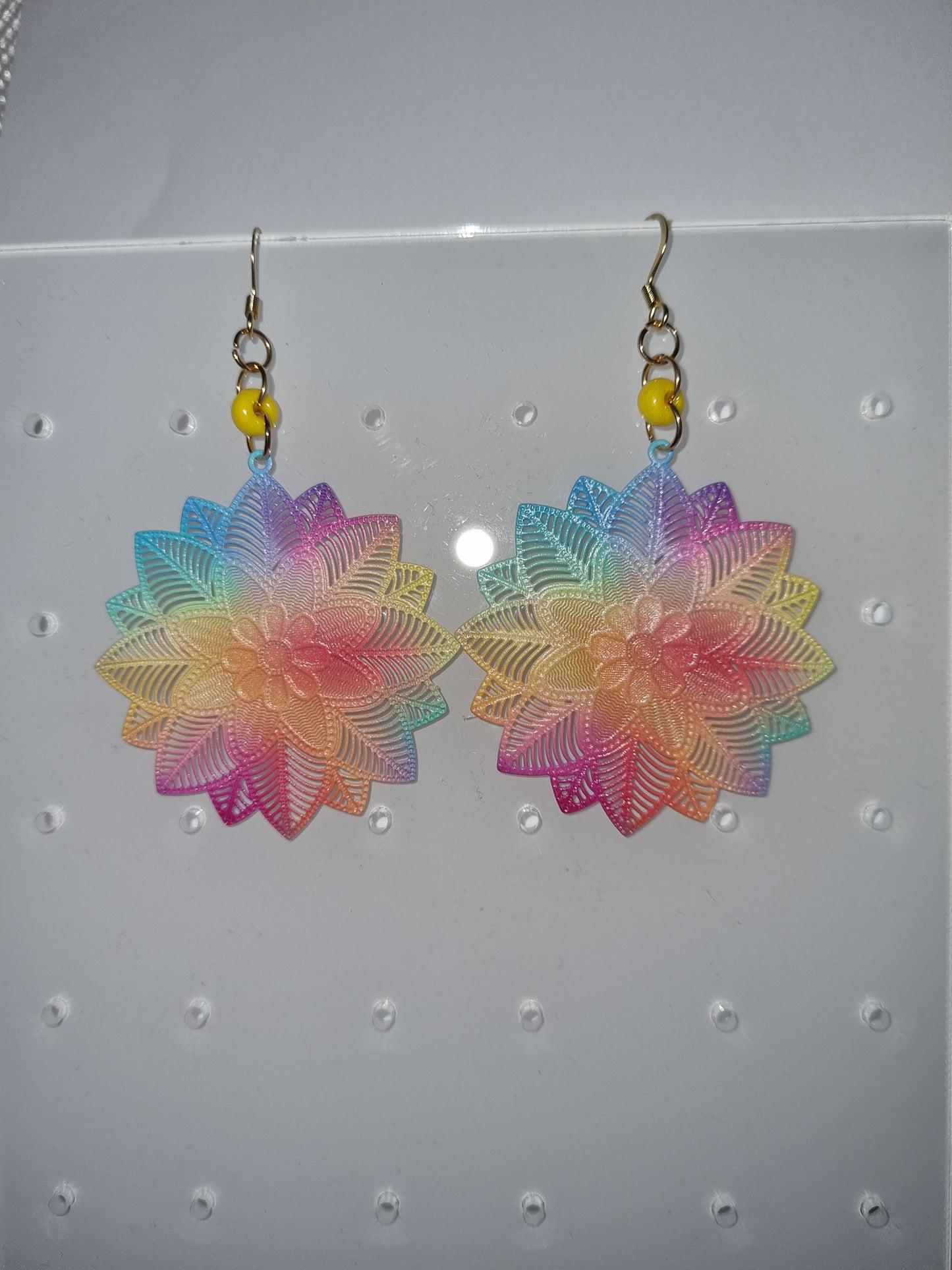 Boucles d'oreilles fantaisie multi couleurs et une perle jaune .